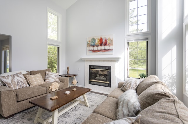 living room featuring a high ceiling, a tiled fireplace, and wood finished floors