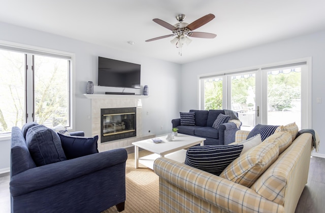living room with baseboards, a fireplace, a ceiling fan, and wood finished floors