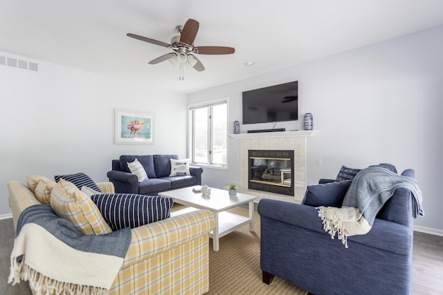 living room featuring a fireplace, visible vents, ceiling fan, wood finished floors, and baseboards