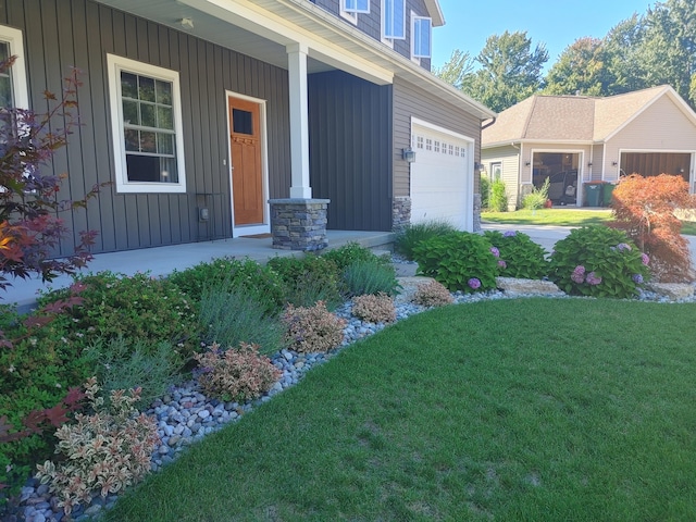 doorway to property with board and batten siding, covered porch, a yard, and a garage