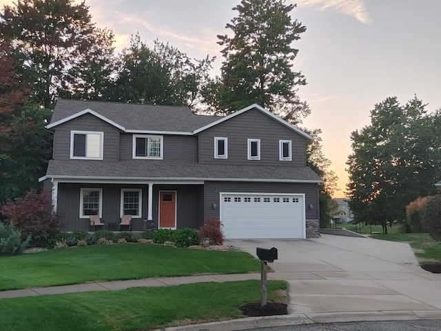 view of front of house with driveway, a lawn, roof with shingles, an attached garage, and a porch