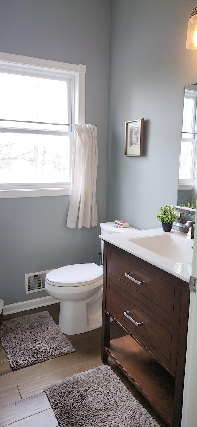 half bath featuring toilet, visible vents, and vanity