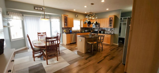 kitchen featuring a center island, stainless steel appliances, dark countertops, tasteful backsplash, and a sink