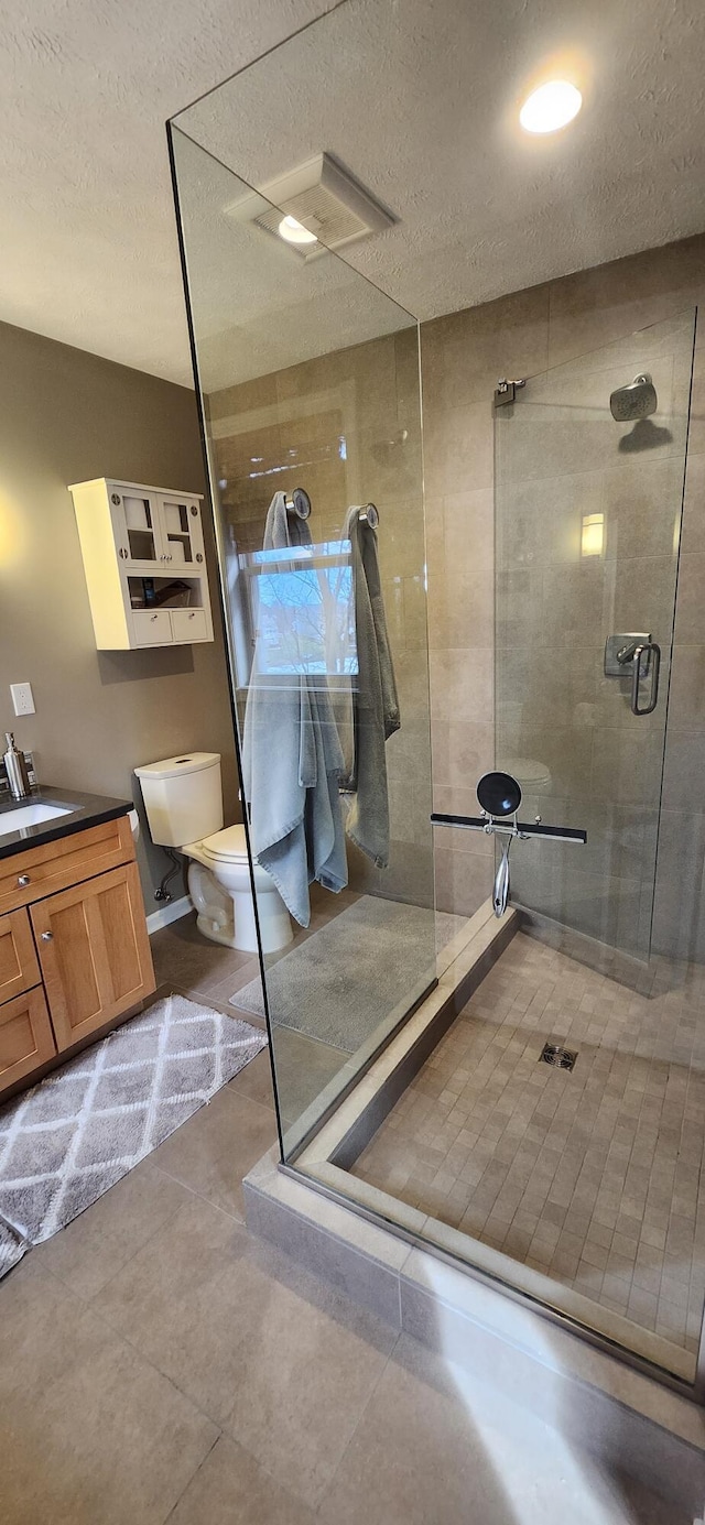 full bath with visible vents, toilet, a textured ceiling, a shower stall, and vanity