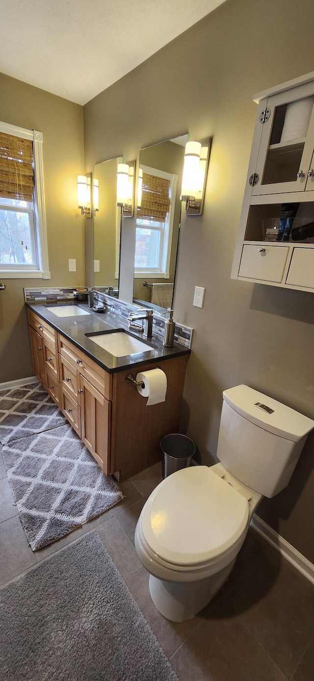 bathroom with double vanity, tile patterned flooring, a sink, and toilet