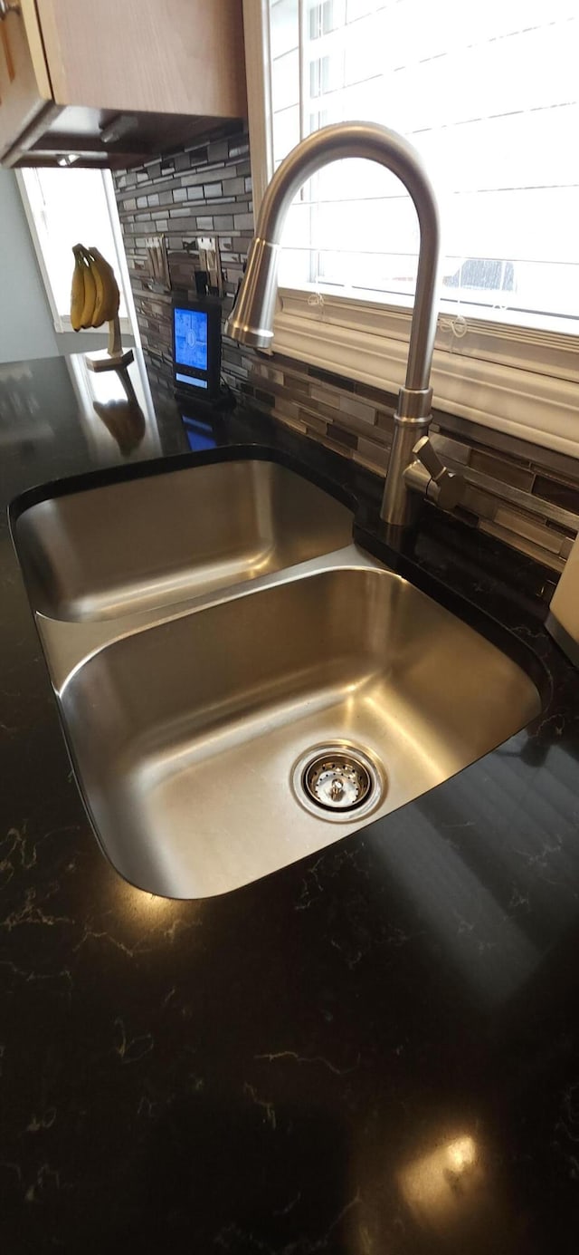 interior details featuring backsplash, dark countertops, and a sink