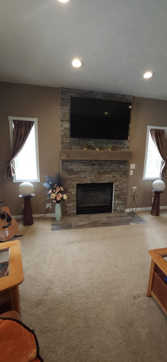 carpeted living area featuring a wealth of natural light, a fireplace, and baseboards