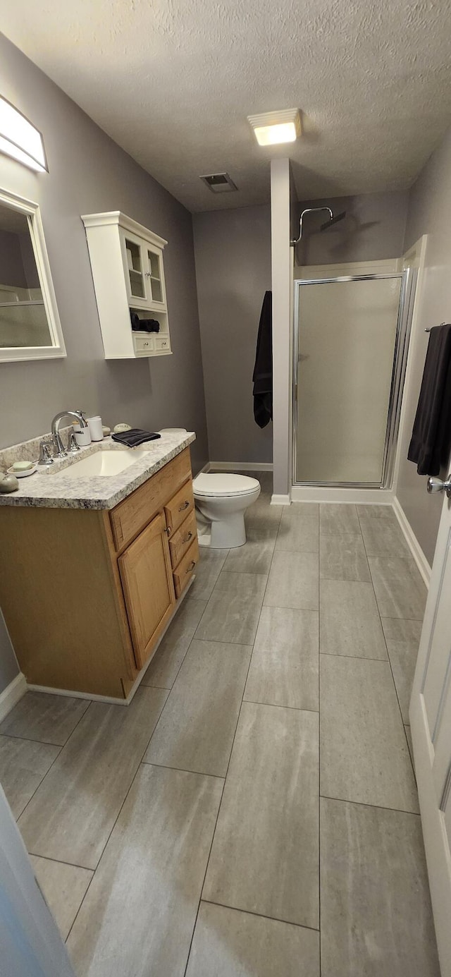 full bath featuring visible vents, toilet, an enclosed shower, vanity, and baseboards