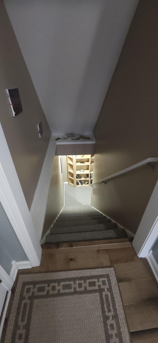 staircase with lofted ceiling and wood finished floors