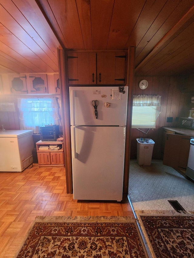 kitchen featuring visible vents, wooden ceiling, freestanding refrigerator, white fridge, and wood walls