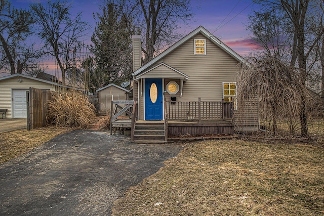 view of front of house with an outbuilding, a chimney, and a wooden deck