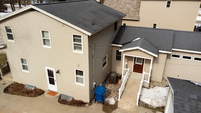 view of front of home with cooling unit and roof with shingles