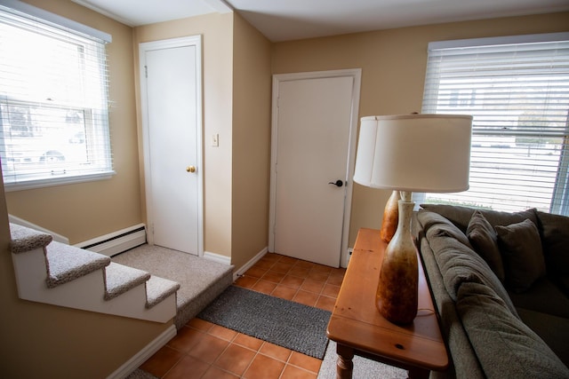 living area featuring light tile patterned floors, stairway, a wealth of natural light, and a baseboard heating unit