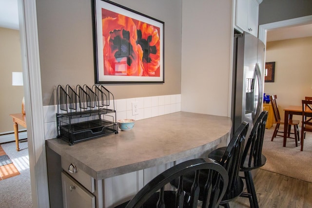 home office with a baseboard heating unit and dark wood-style flooring