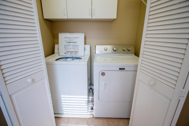 washroom with cabinet space, tile patterned flooring, and washer and dryer