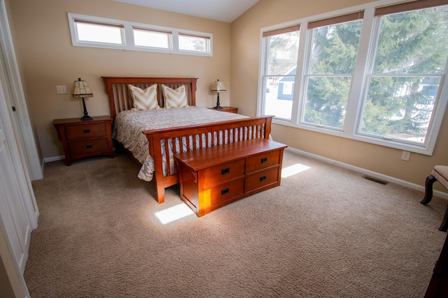 carpeted bedroom featuring lofted ceiling, visible vents, and baseboards