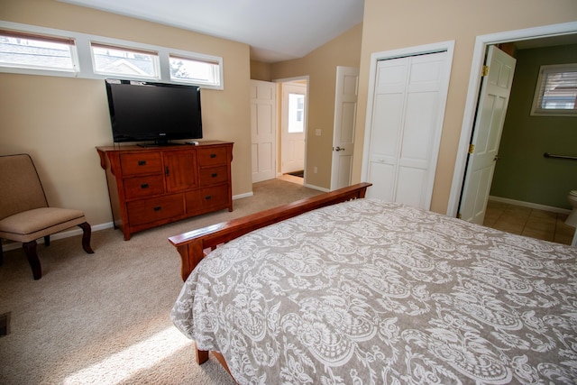 carpeted bedroom featuring lofted ceiling, a closet, connected bathroom, and baseboards