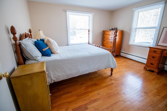 bedroom with light wood finished floors and a baseboard heating unit