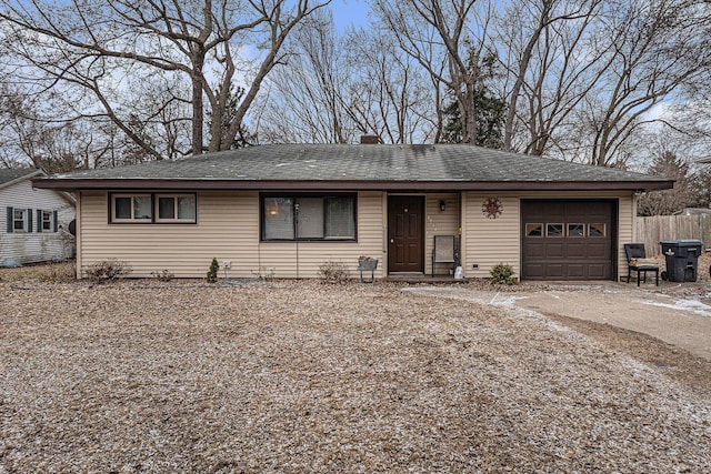 ranch-style home with concrete driveway, roof with shingles, an attached garage, and fence