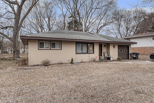 view of front of property with a garage, driveway, a shingled roof, and fence