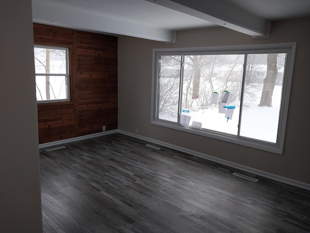 spare room with visible vents, dark wood-style flooring, beam ceiling, and baseboards