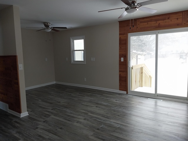 unfurnished living room featuring a ceiling fan, dark wood-style flooring, visible vents, and baseboards