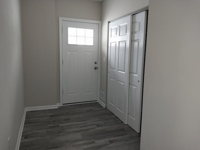 doorway with baseboards, visible vents, and dark wood-type flooring