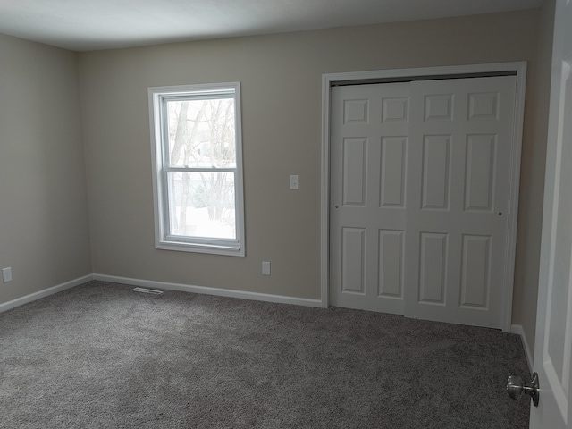 unfurnished bedroom featuring a closet, carpet flooring, visible vents, and baseboards