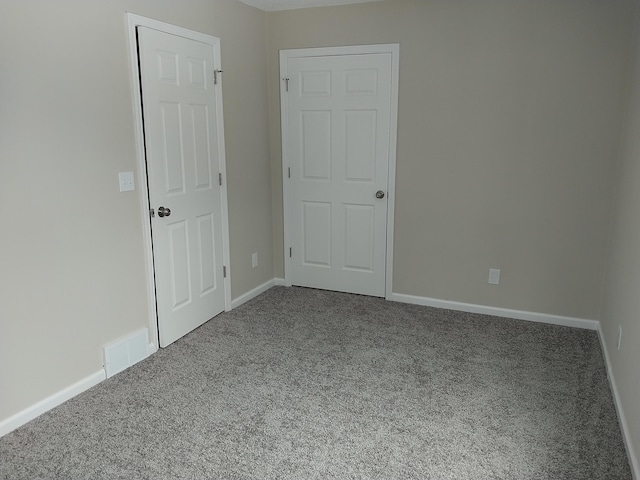 carpeted spare room featuring visible vents and baseboards