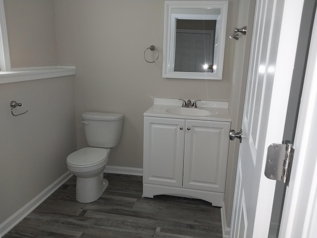 bathroom with wood finished floors, vanity, toilet, and baseboards