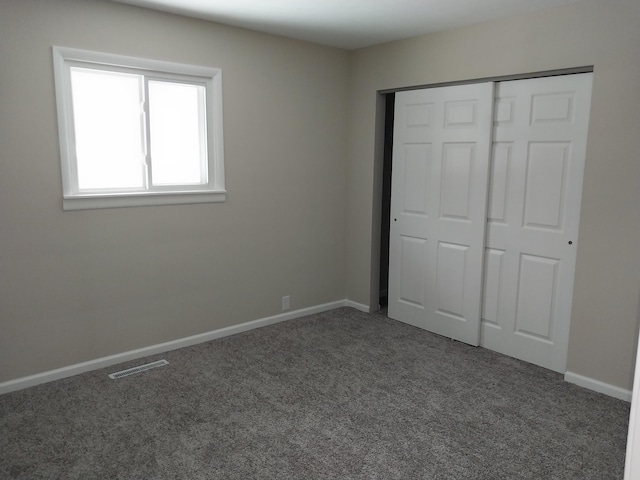 unfurnished bedroom with a closet, carpet, visible vents, and baseboards