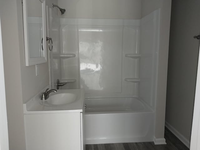 bathroom with shower / tub combination, wood finished floors, vanity, and baseboards