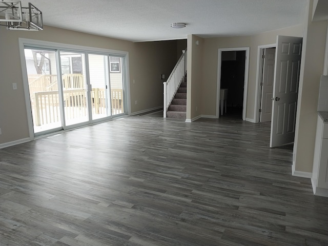 spare room featuring stairs, baseboards, dark wood finished floors, and a textured ceiling