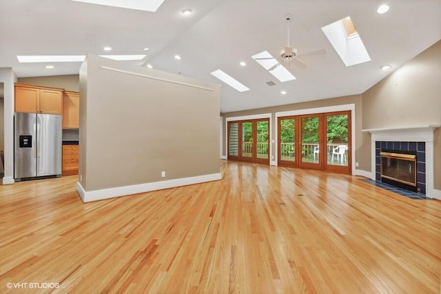 unfurnished living room with baseboards, recessed lighting, a tiled fireplace, and light wood-style floors