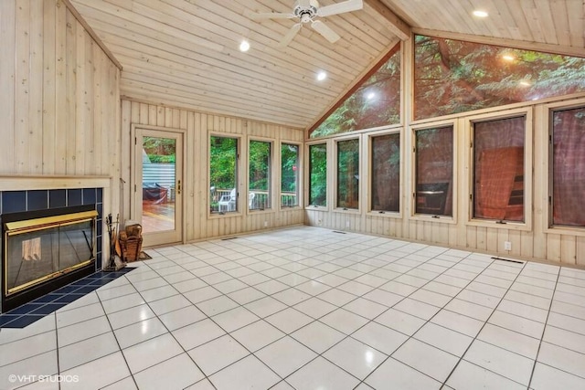 unfurnished sunroom featuring a ceiling fan, wood ceiling, vaulted ceiling with beams, and a tiled fireplace