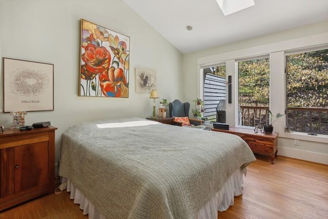 bedroom featuring light wood-type flooring, lofted ceiling with skylight, and baseboards