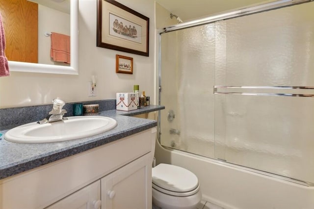 bathroom with enclosed tub / shower combo, vanity, and toilet