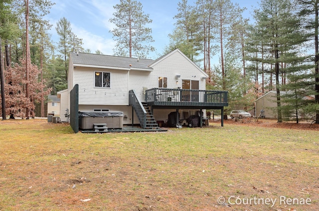 rear view of house with a lawn, a hot tub, a wooden deck, and stairs