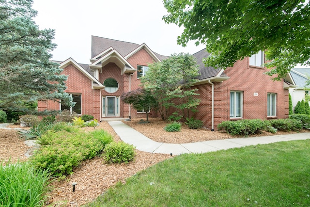 view of front of house with brick siding, a front lawn, and a shingled roof