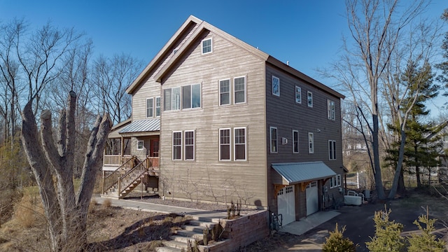 view of front of house with stairs, metal roof, aphalt driveway, and an attached garage