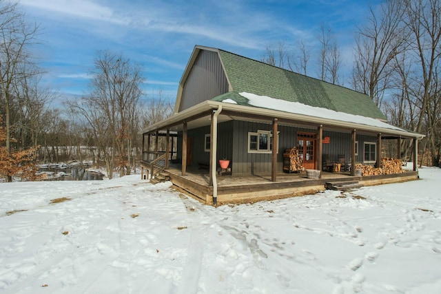 exterior space featuring covered porch, a shingled roof, board and batten siding, and a gambrel roof