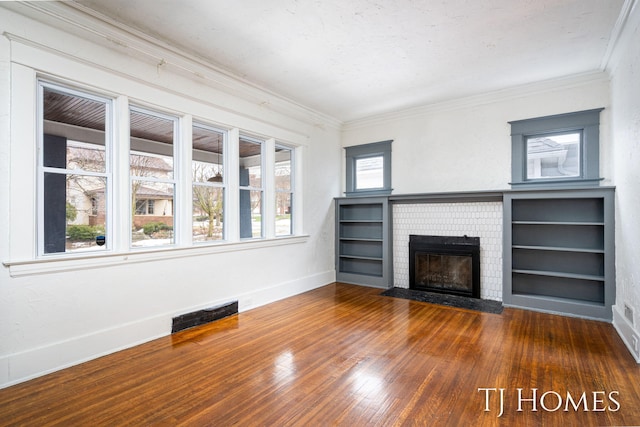 unfurnished living room featuring visible vents, hardwood / wood-style floors, ornamental molding, a brick fireplace, and baseboards