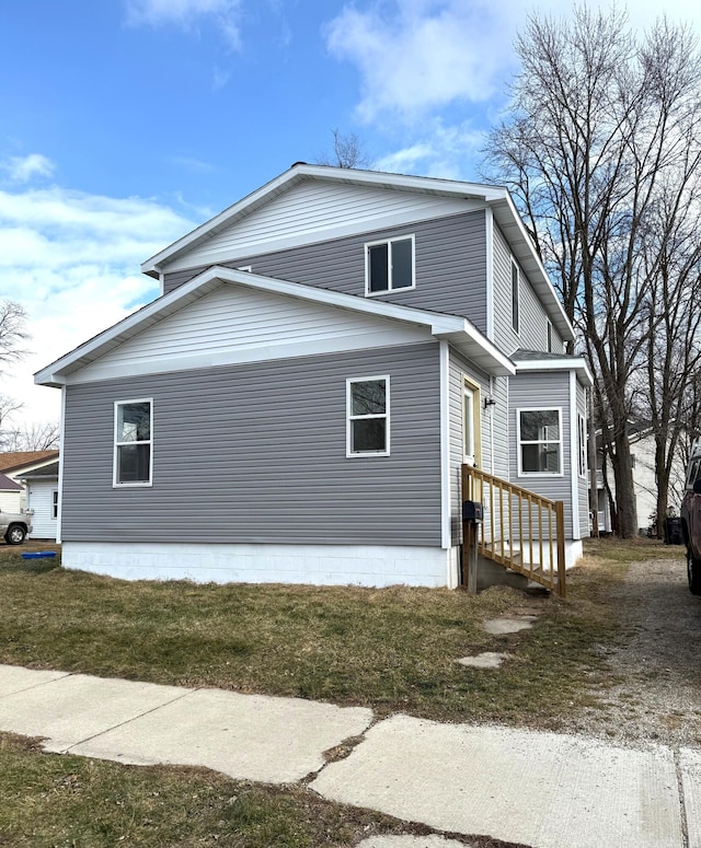 view of side of property with entry steps and a lawn