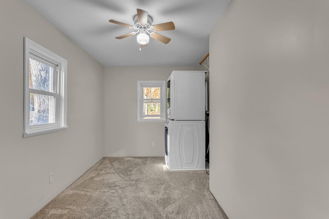 empty room with carpet, ceiling fan, and stacked washing maching and dryer