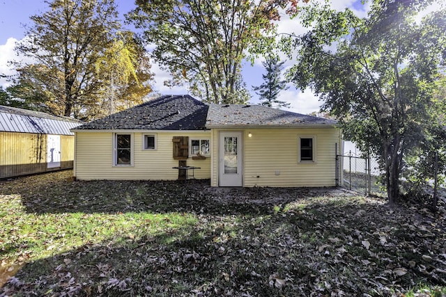 back of property with a gate and fence