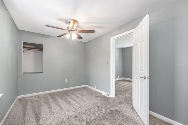 carpeted empty room featuring ceiling fan, visible vents, and baseboards