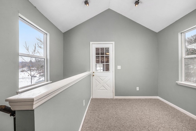 hall with lofted ceiling, baseboards, carpet flooring, and a healthy amount of sunlight