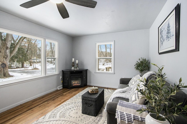 interior space with a glass covered fireplace, wood finished floors, visible vents, and baseboards