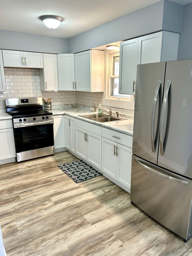 kitchen featuring stainless steel appliances, light countertops, a sink, and light wood-style flooring