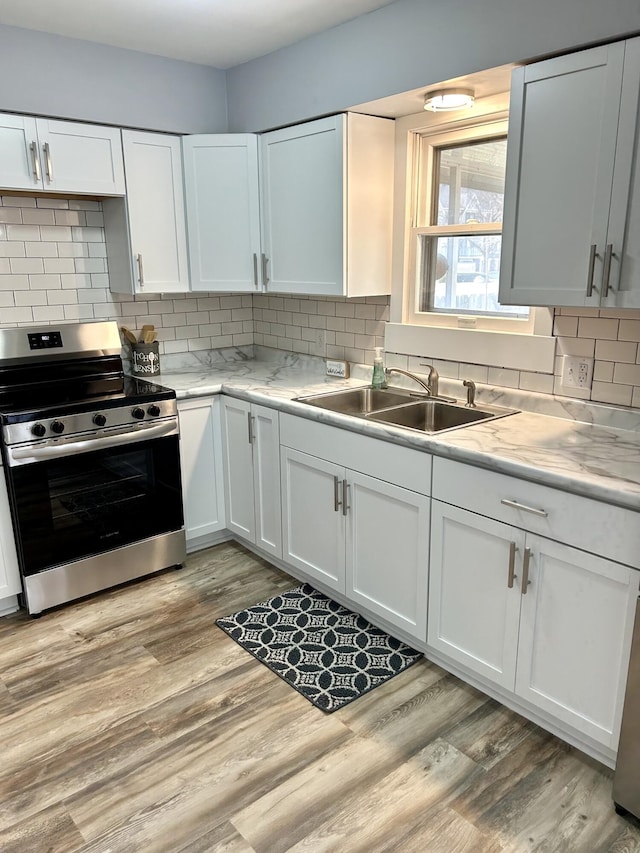 kitchen with light wood-style floors, electric range, white cabinetry, and a sink